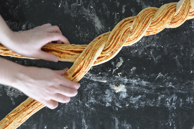 top view image of hands holding bread dough creatively designed like braided hair