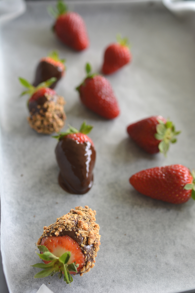 overhead view of chocolate-coated strawberries, garnished with crushed nuts, and accompanied by fresh strawberries
