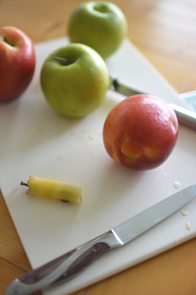 image of four fresh apples, two green and two red. One apple is cored with a knife beside them