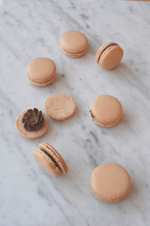 image showing a top-down view of french macarons, with some macarons filled with chocolate ganache