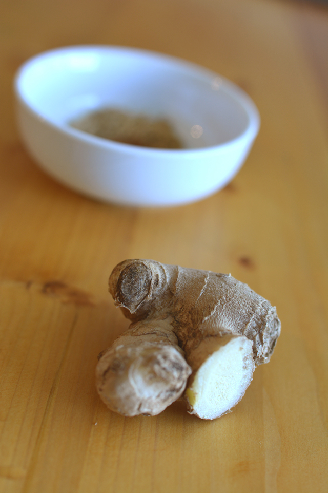 a piece of cut ginger and a bowl with powder 