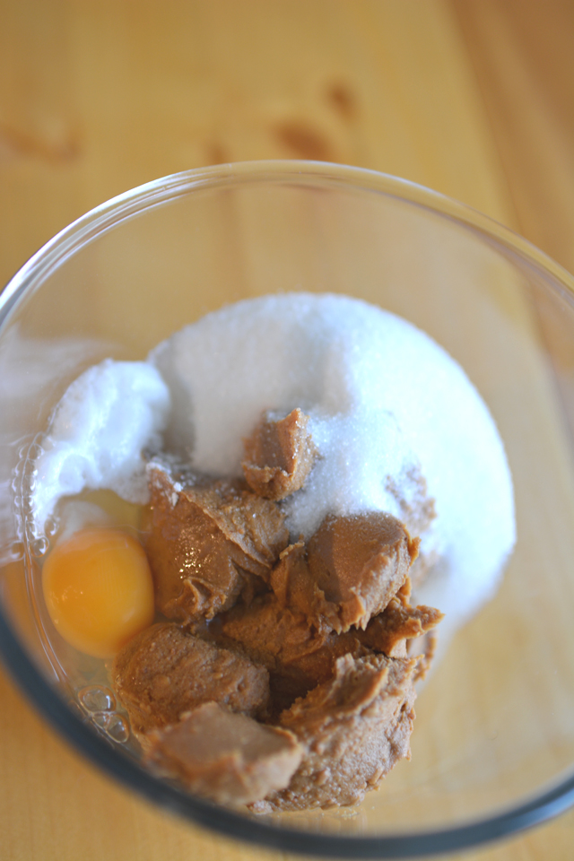 top down image of a bowl containing of peanut butter, chocolate and pistachio cookies ingredients; egg, sugar, penut butter