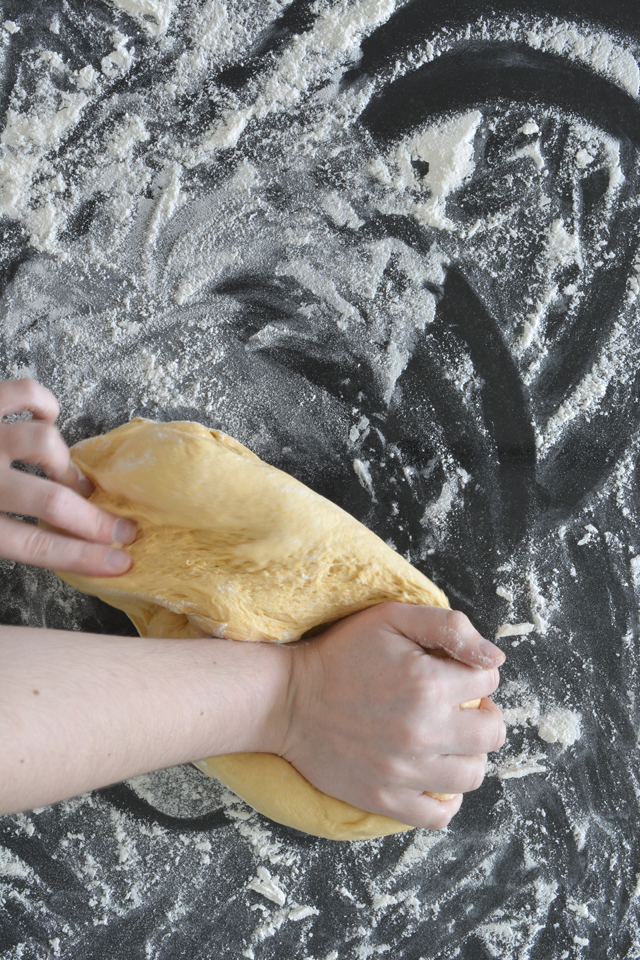 top view image of hands kneading dough with scattered flour