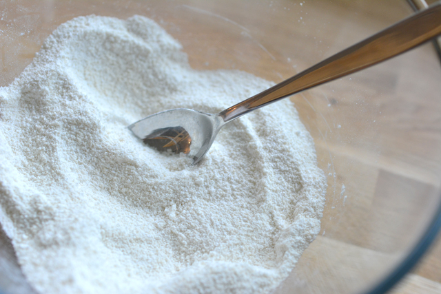 close-up view of a bowl containing a mixture of ground almonds and icing sugar, with a spoon resting inside