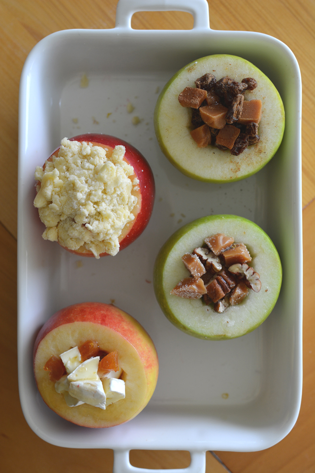 overhead view of four whole fresh apples filled with toppings in the hollowed-out cores