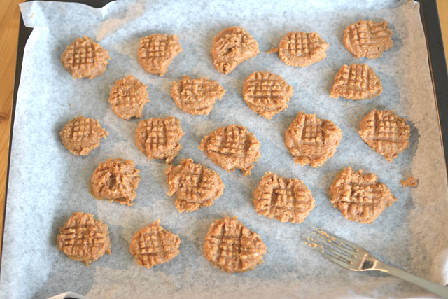 top-down view of a group of cookie batter dollops, each pressed with a fork for a textured appearance