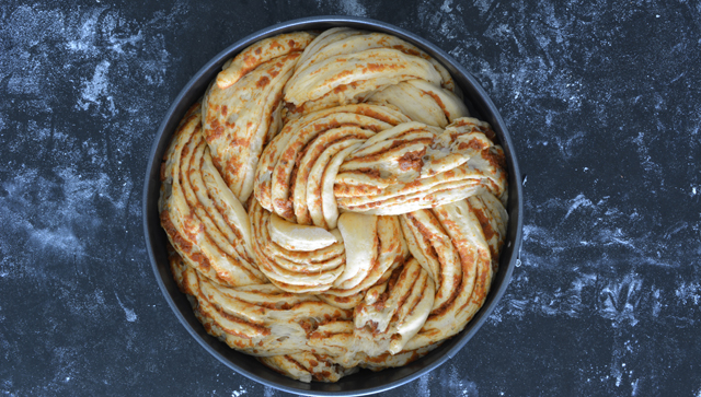 top view of a round cake pan filled with braided bread dough resembling a hair-like pattern