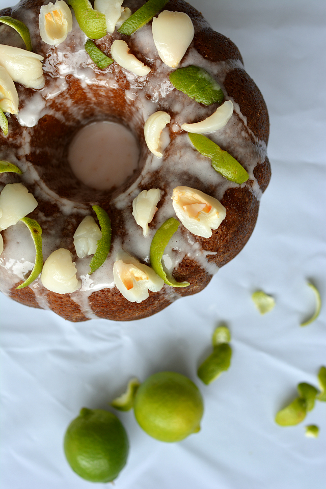 top-down view of a Lime and Lychee Cake with a drizzle of icing, garnished with lychee and lime zest, and accompanied by fresh lime