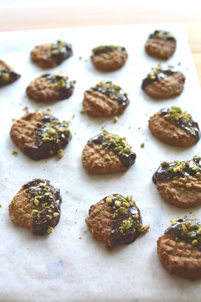 group of peanut butter, chocolate and pistachio cookies with a half-dipped chocolate coating and garnished with crushed pistachios