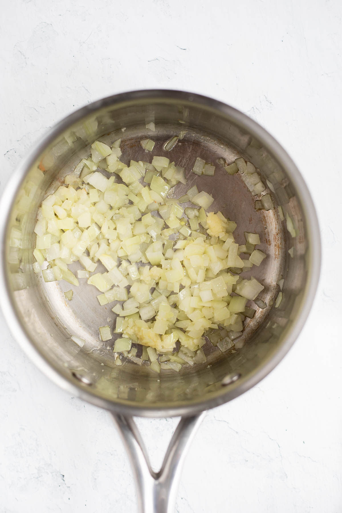 Onions being sautéed in a saucepan, top view.