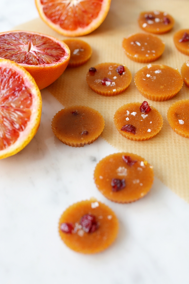 close-up image of a batch of salted blood orange toffees with slices of orange placed beside them