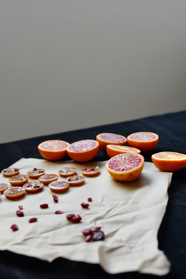 salted blood orange toffees arranged on a piece of cloth with slices of fresh oranges placed next to it