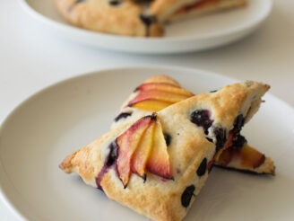 Blueberry and nectarine scones on a stone colored plate with more scones in the background on a white table