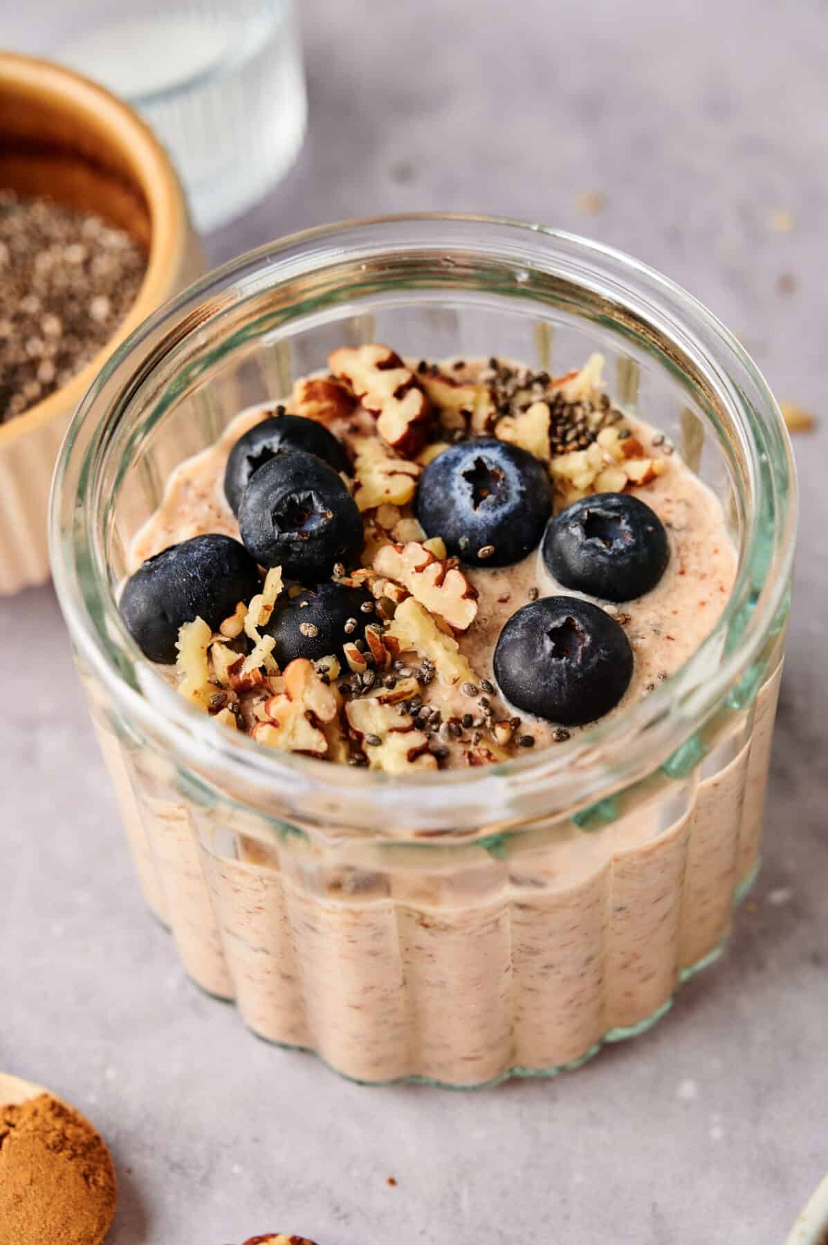 Breakfast Chia Pudding in a glass jar topped with fresh blueberries and pecans.