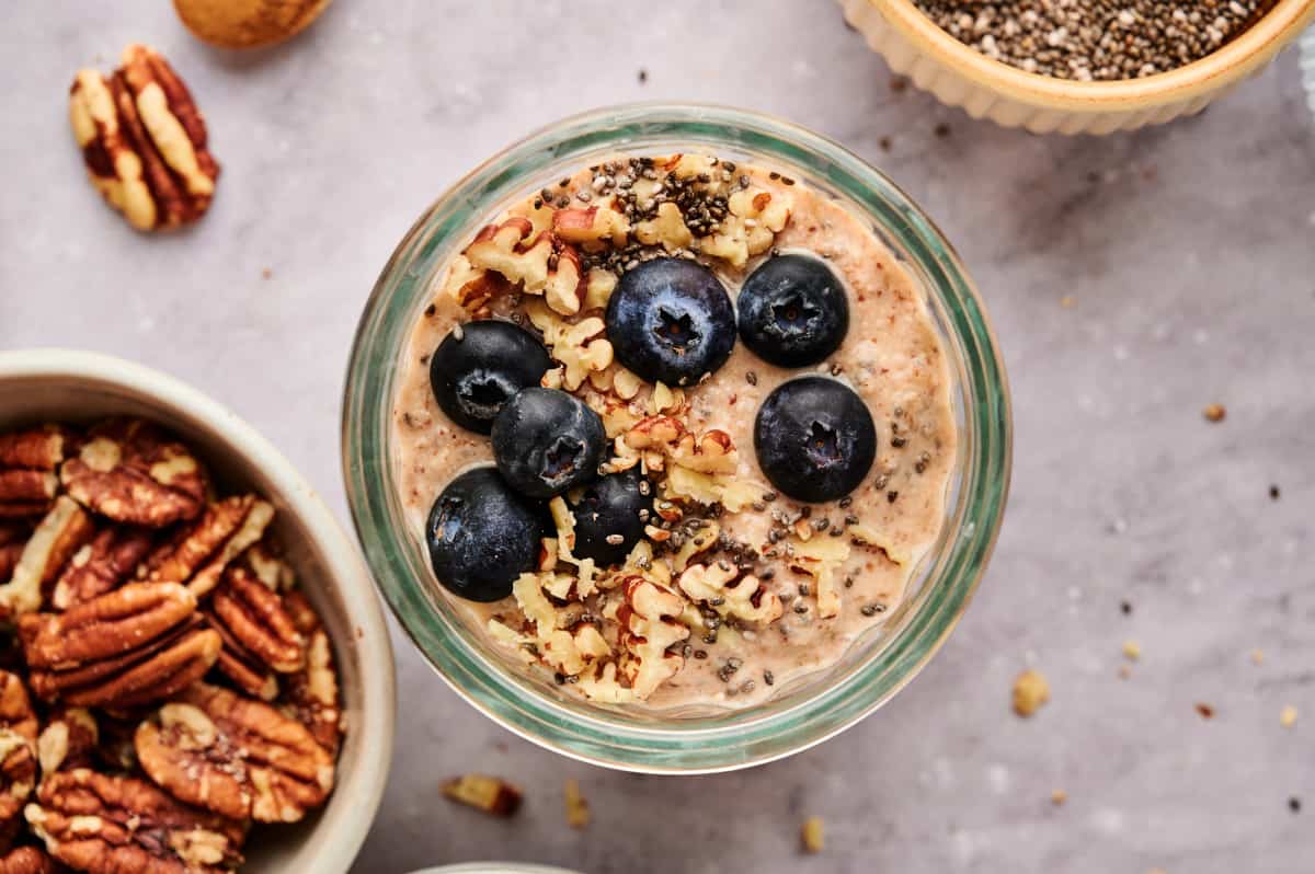 Breakfast Chia Pudding in a glass jar topped with fresh blueberries and pecans.