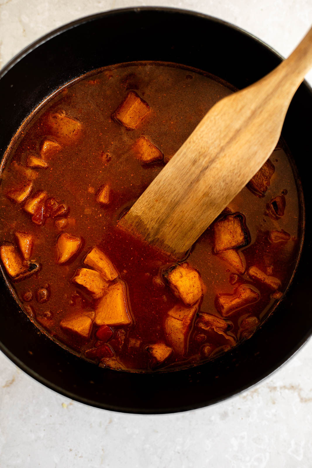 Butternut squash and black beans added to chili mixture in a Dutch oven.