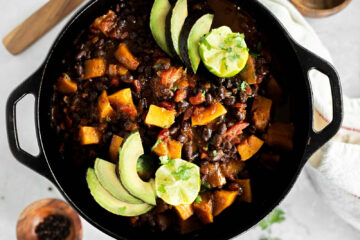 Black Bean and Butternut Squash Chili in a Dutch oven topped with Avocado and lime.