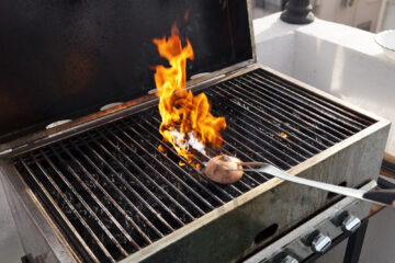 Cleaning the grates of a BBQ grill with an onion.