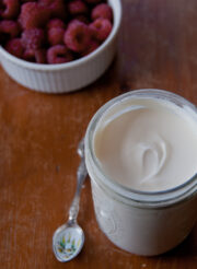 DIY crème fraîche in a glass jar with raspberries.