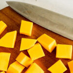 Butternut squash cut into cubes on a cutting board.