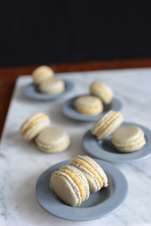 close-up of a colorful assortment of macarons arranged in pairs on a small plate. each macaron is generously filled with ganache