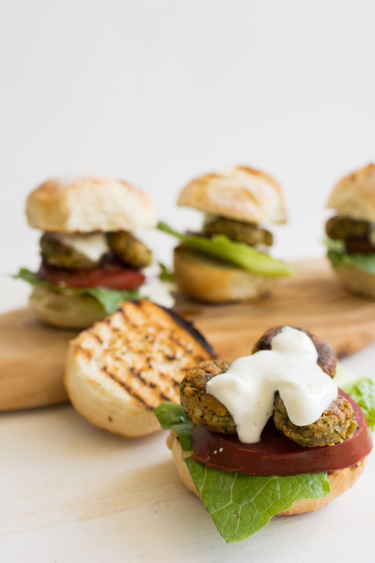 an image of homemade falafel on top of a burger bun topped with a creamy, and tahini dressing