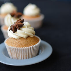 close-up photograph of a chai tea spiced cupcake topped with buttercream and a decorative star anise, beautifully presented on a cupcake plate