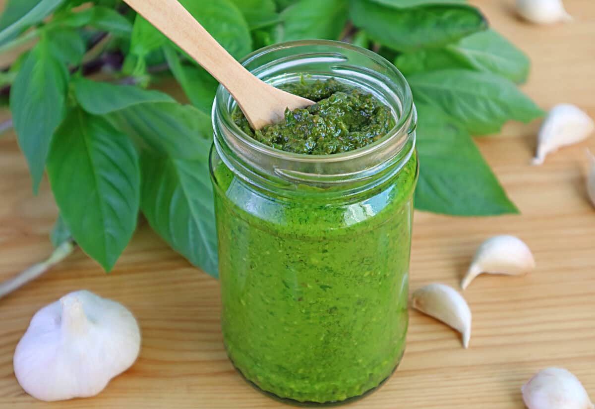 Homemade Fresh Basil Pesto Sauce in a Glass Bottle on Wooden Table.