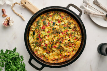 A fully cooked garden veggie frittata in a cast iron skillet.