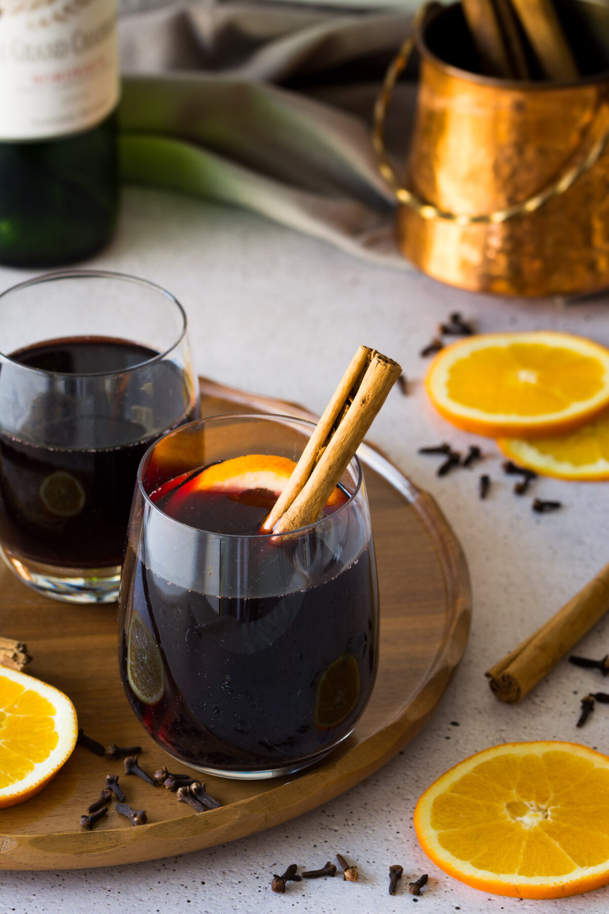 two glasses of german mulled wine with a cinnamon stick and slices of lemons nearby