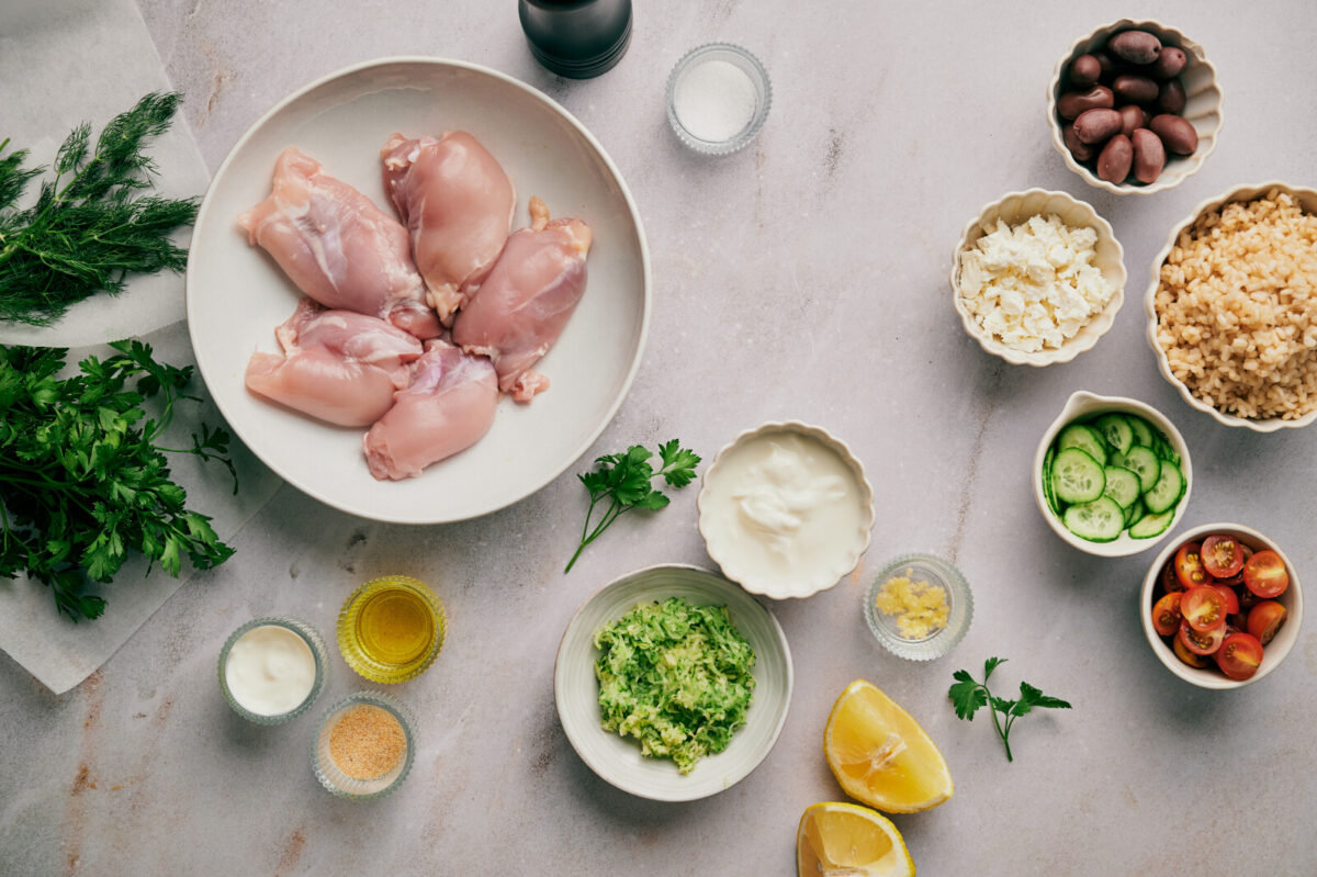 Ingredients for Greek Chicken Bowls in various bowls and plates.