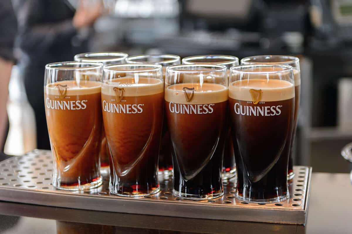 A row of Guinness beer in pint glasses.