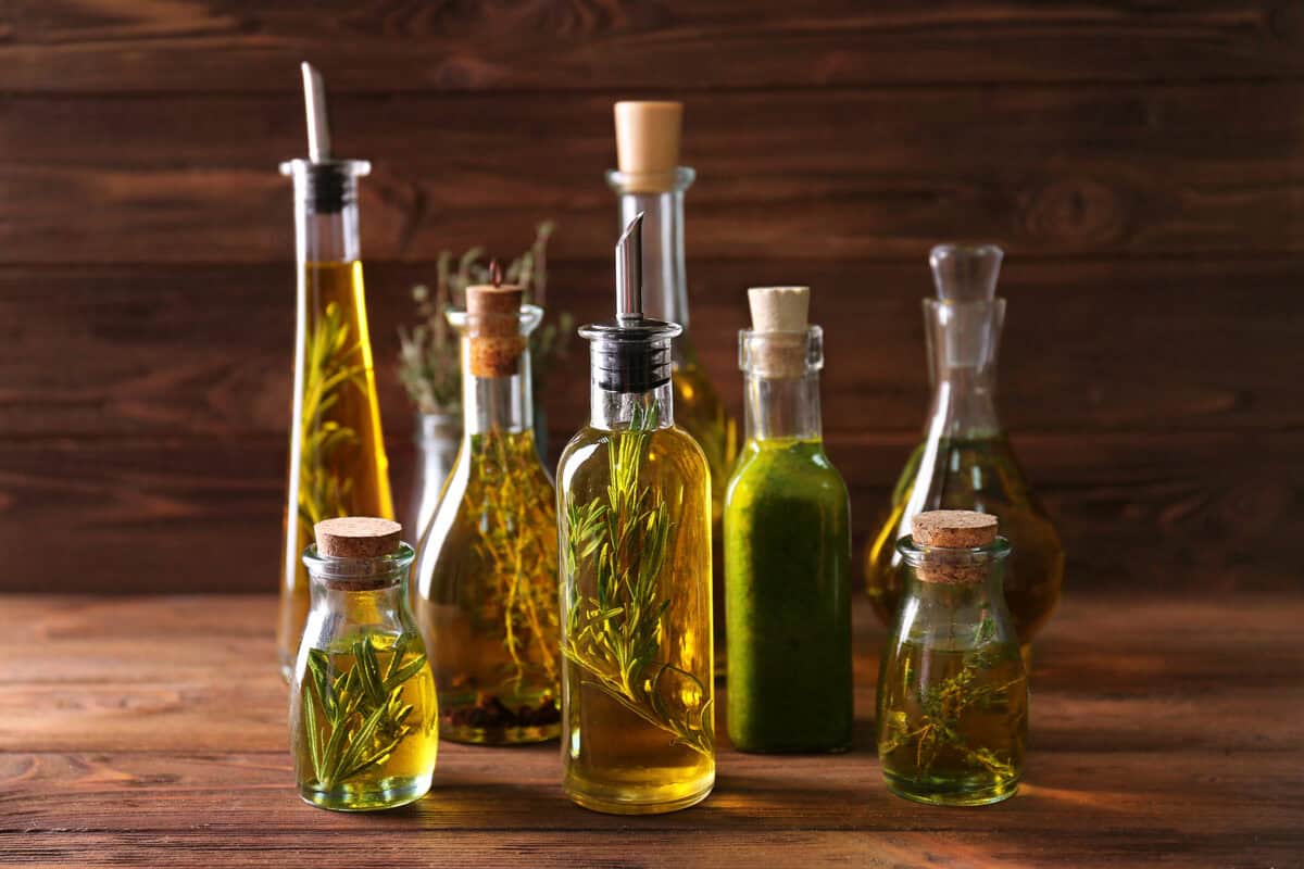 Bottles of herb-infused olive oil on wooden background.