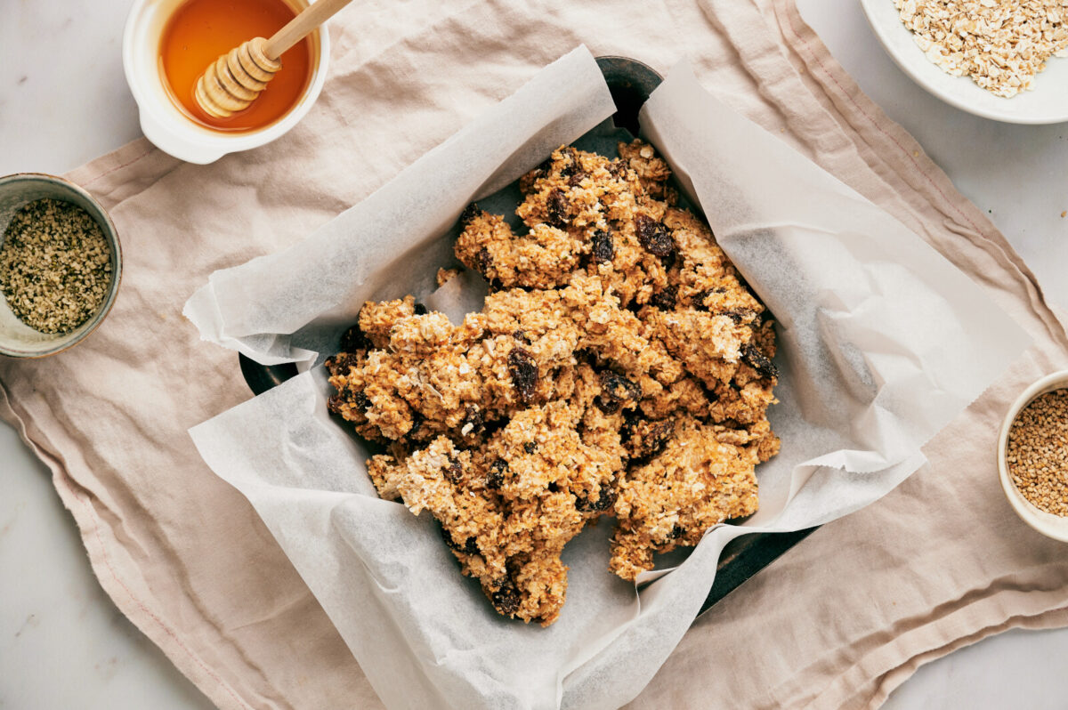 Homemade granola bar mixture poured into a parchment lined 8x8 baking pan.