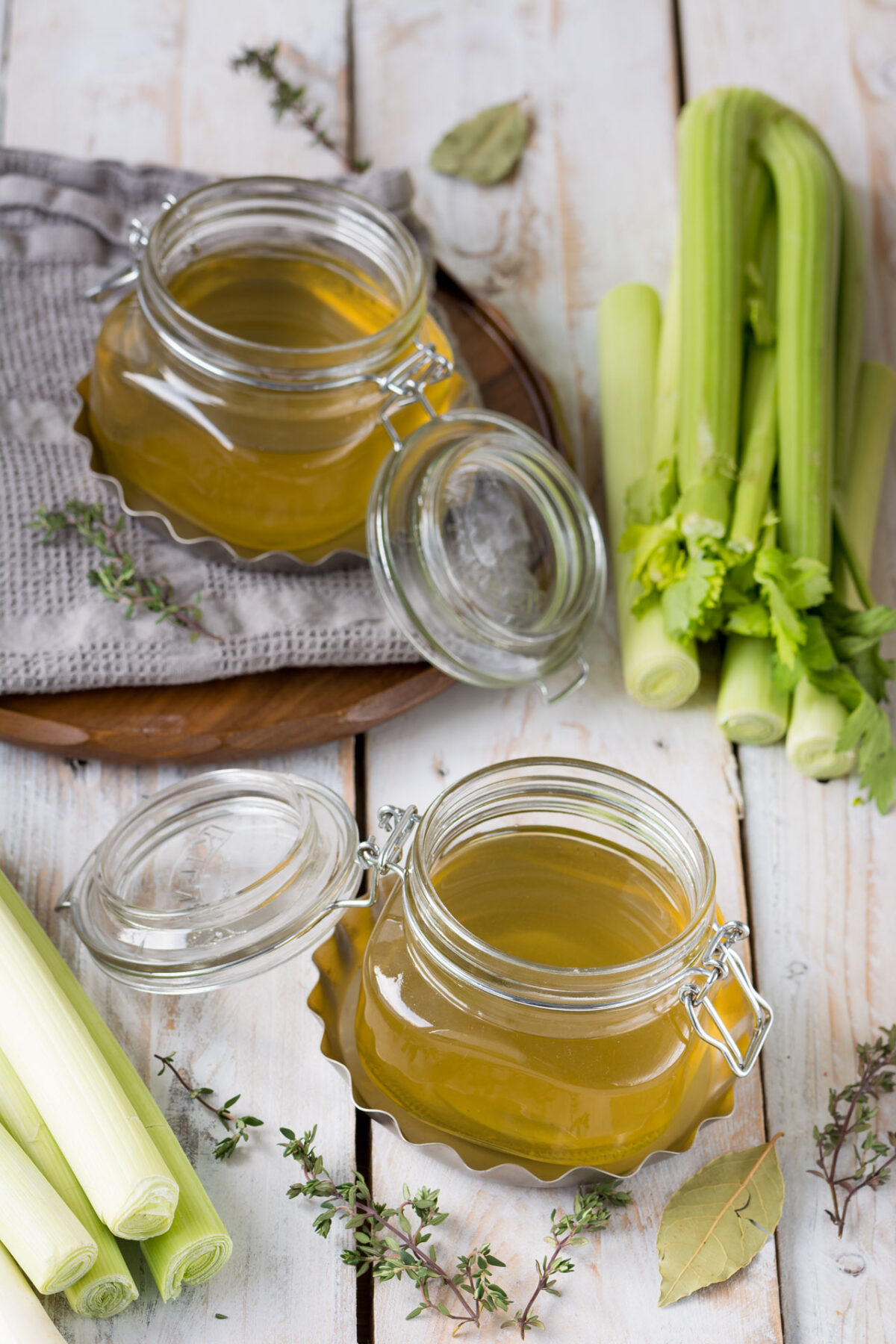 top-down view of two canisters filled with homemade vegetable stock, accompanied by fresh celery ribs placed nearby