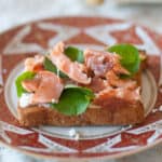 Hot smoked salmon on a slice of bread with goat cheese and watercress.