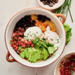 Healthy Spanish Huevos Rancheros with poached eggs, avocadoes, black beans, salsa, and cheesy potatoes.