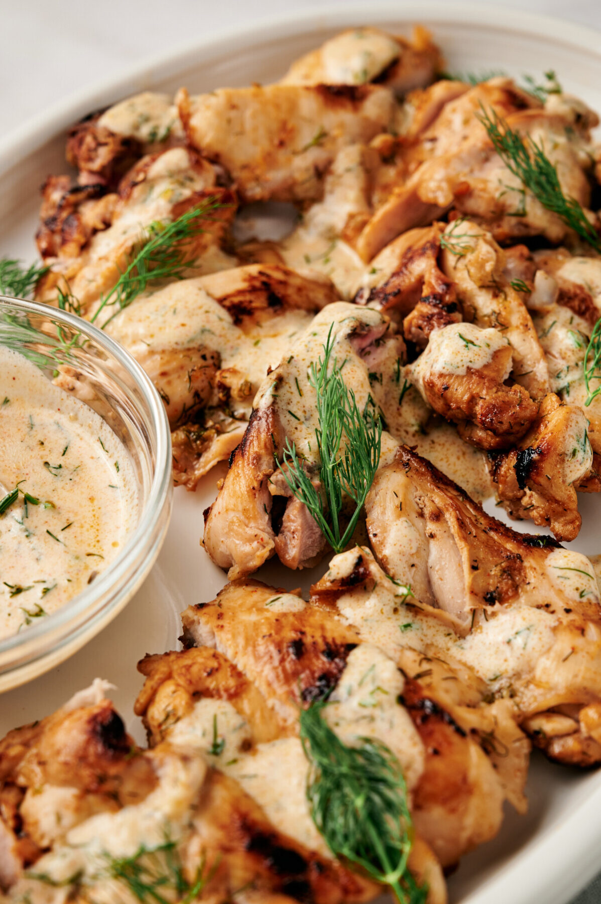 Lemon Dill Chicken on a white plate with sprigs of fresh dill and Dijon yogurt sauce.