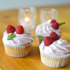 an image of 3 lemon raspberry cupcakes topped with fresh raspberry