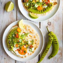 top view image of a plate with naan bread top with corn, eggand grilled peppers beside the plate