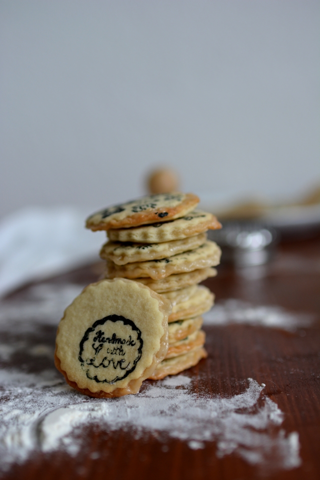 a pile of stamped marzipan layer cookies with one cookie showing an intricate stamp design, and a dusting of flour near the pile
