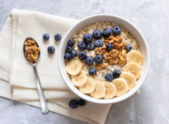 A healthy bowl of oatmeal with bananas, blueberries, and walnuts.