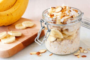 Bananas nut overnight oats with in snap lid glass jar on white marble.