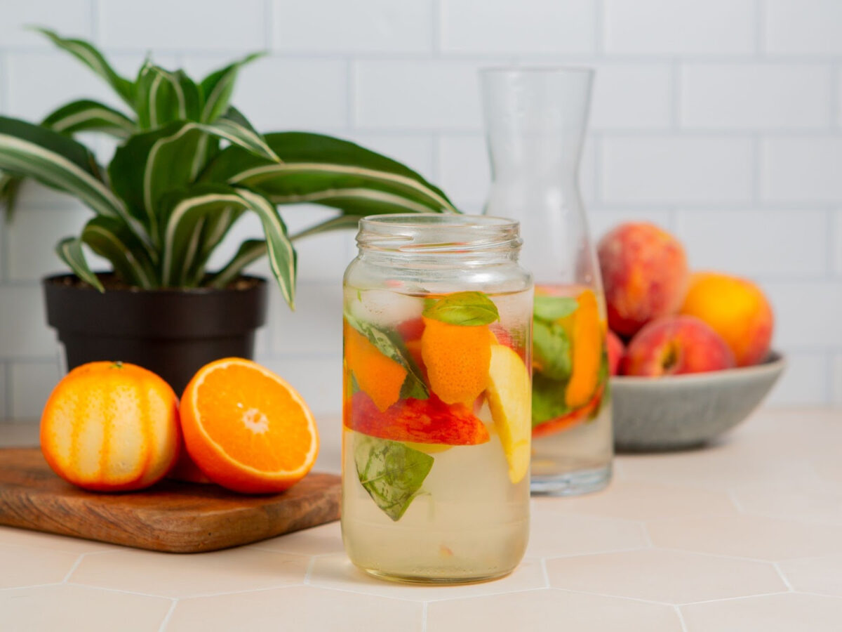 Peach infused water with basil in a glass jar.