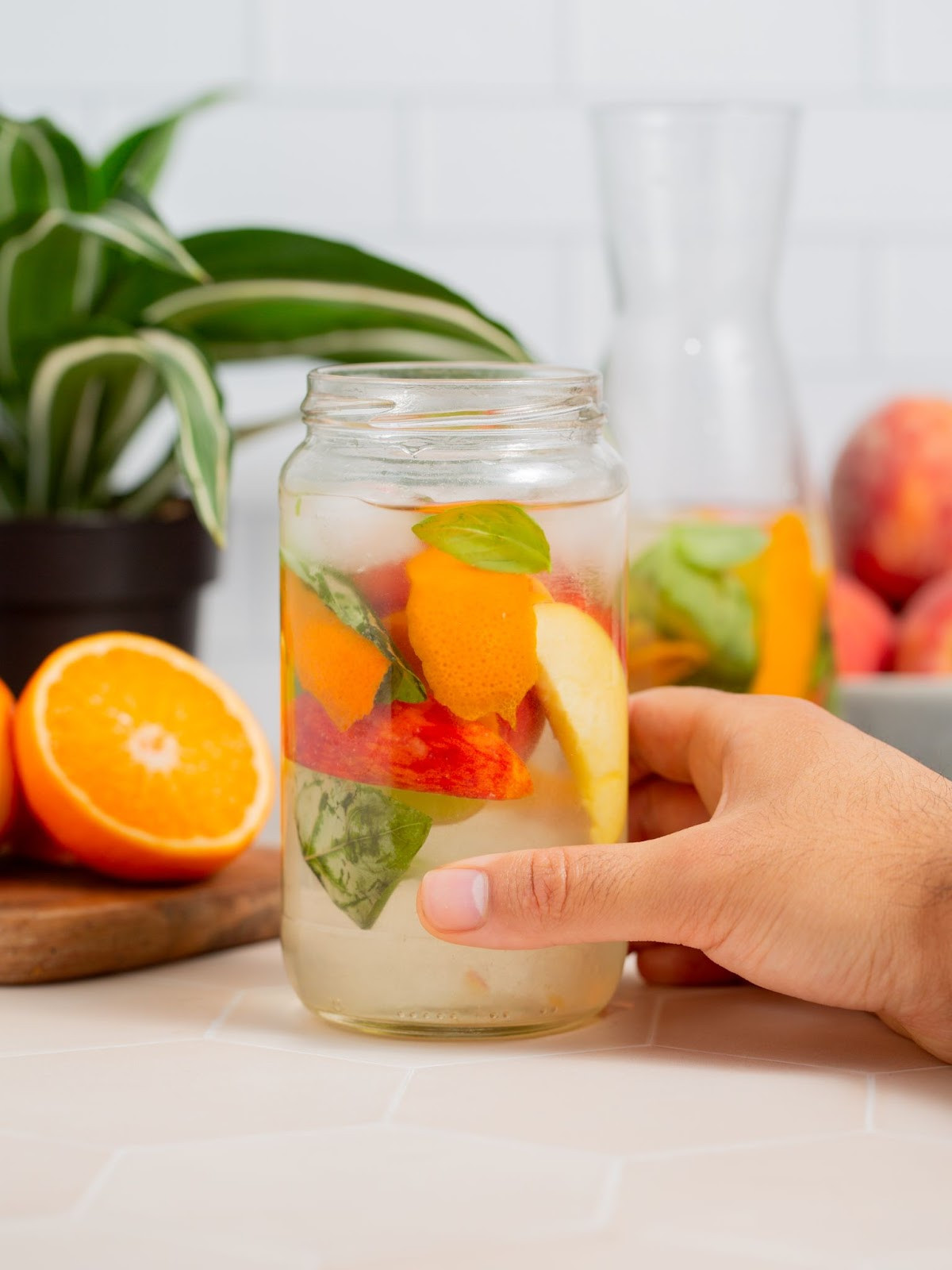 Peach infused water with basil in a glass jar.