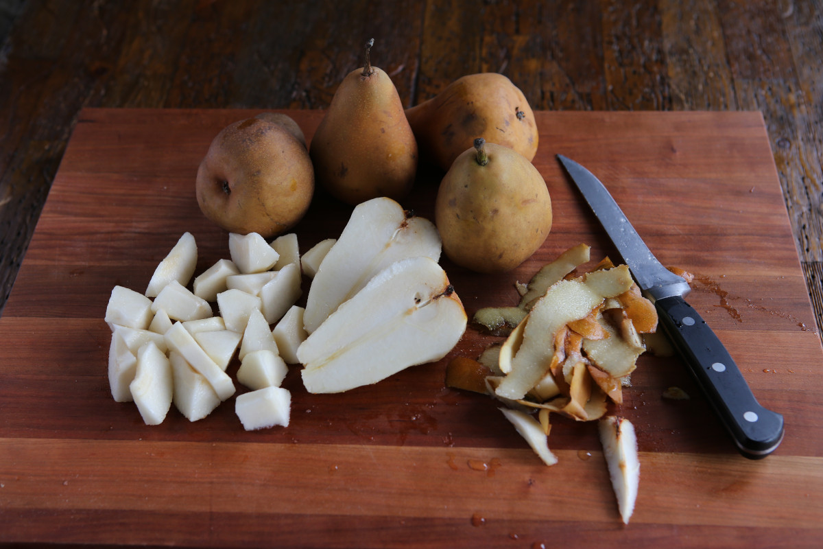 Peeling and cutting up Bosc pears on a wooden cutting board.