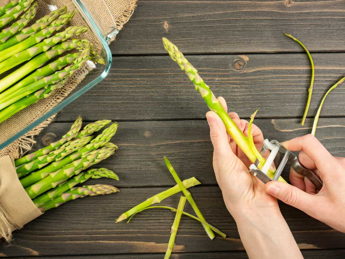 Using a vegetable peeler to peel asparagus stalks.