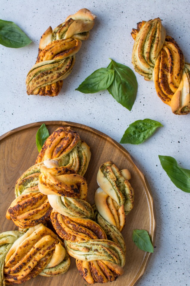 Top view of two-tone pesto bread twists on a countertop with basil leaves.