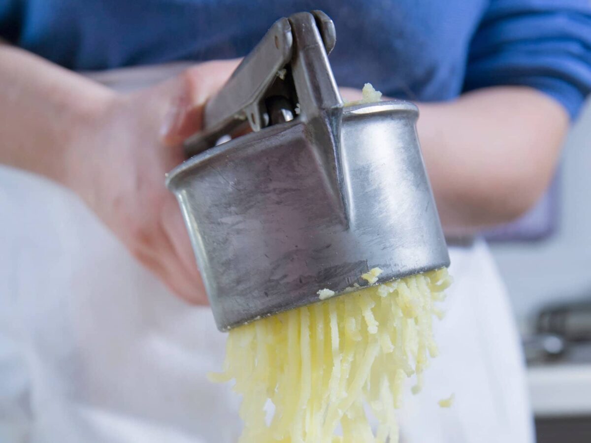 A woman using a potato ricer.