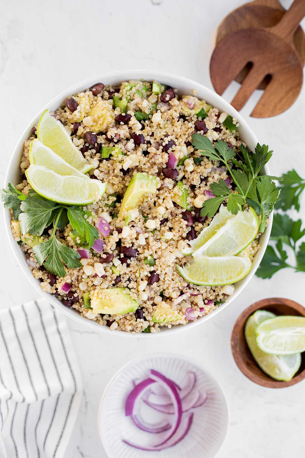 Vertical image of quinoa salad with black beans and corn garnished with lime wedges and cilantro.